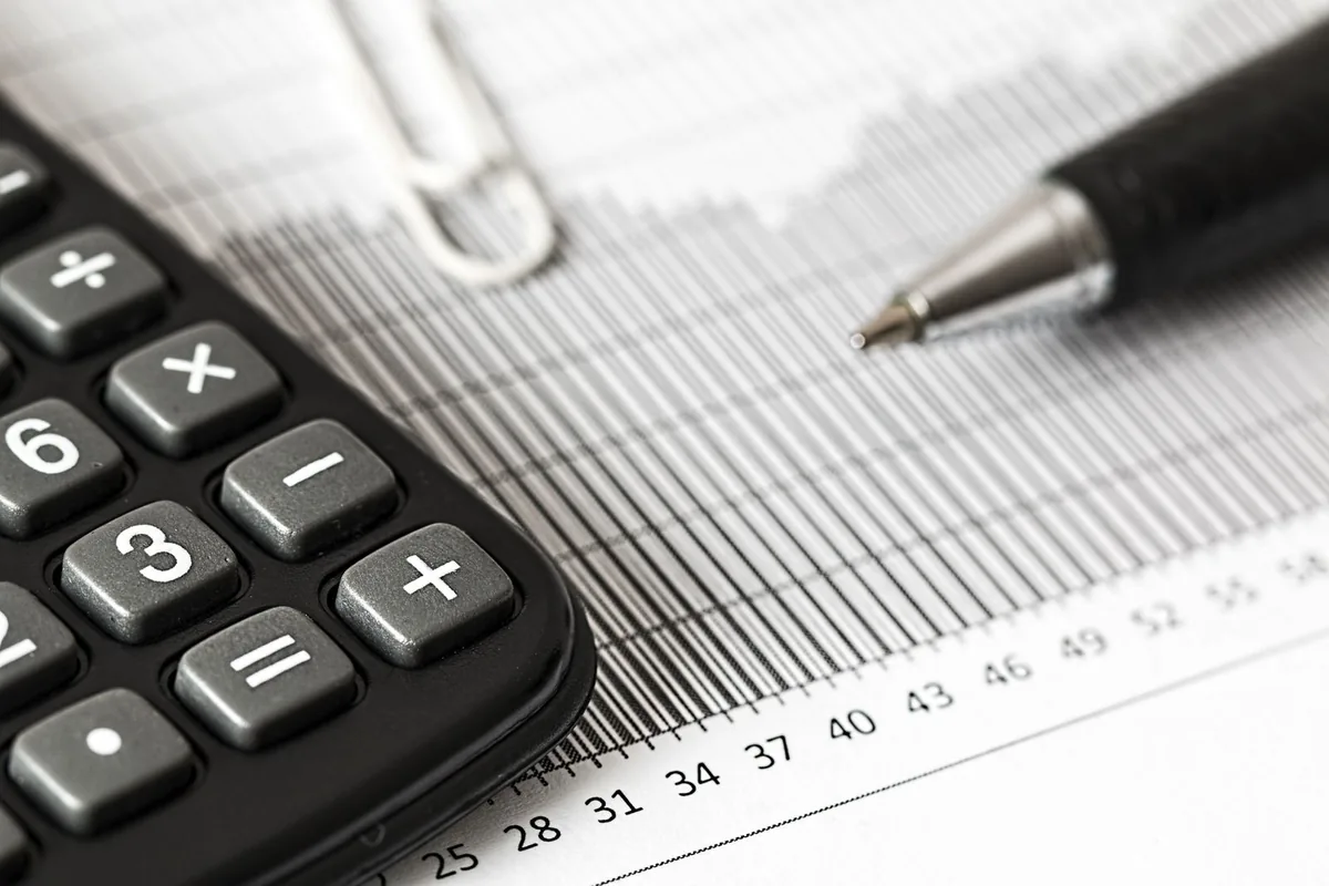A calculator and pen resting on a printed table of figures