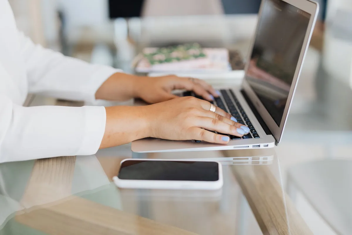 Digital Marketing Agency | ZenWeb Malaysia Hands typing on a laptop beside a smartphone