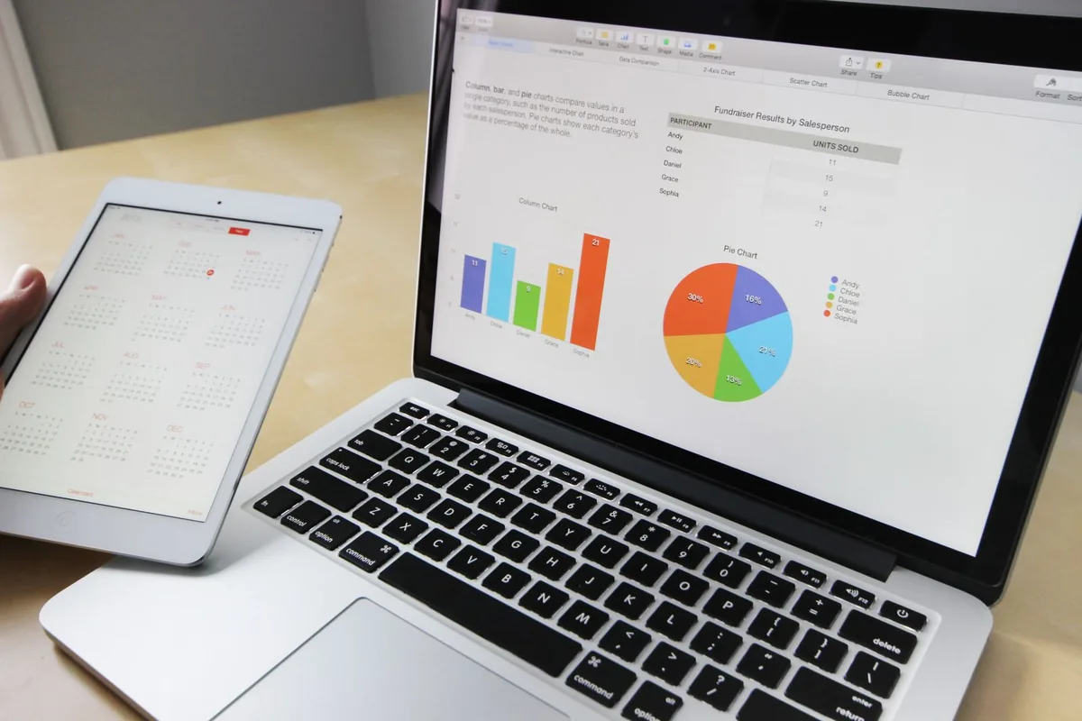 Digital Marketing Agency | ZenWeb Malaysia A laptop open on a desk beside printed business charts
