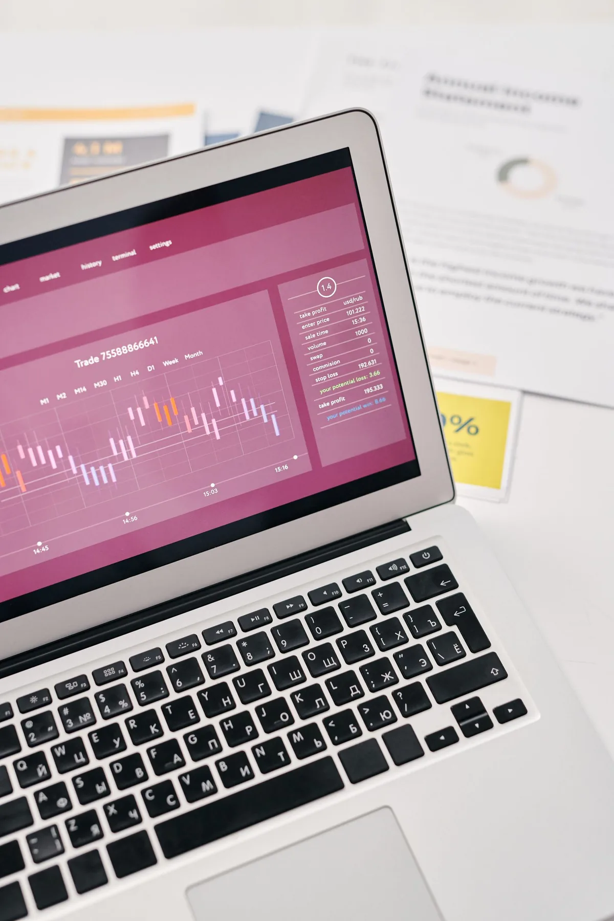 A laptop showing a rising graph beside a notepad