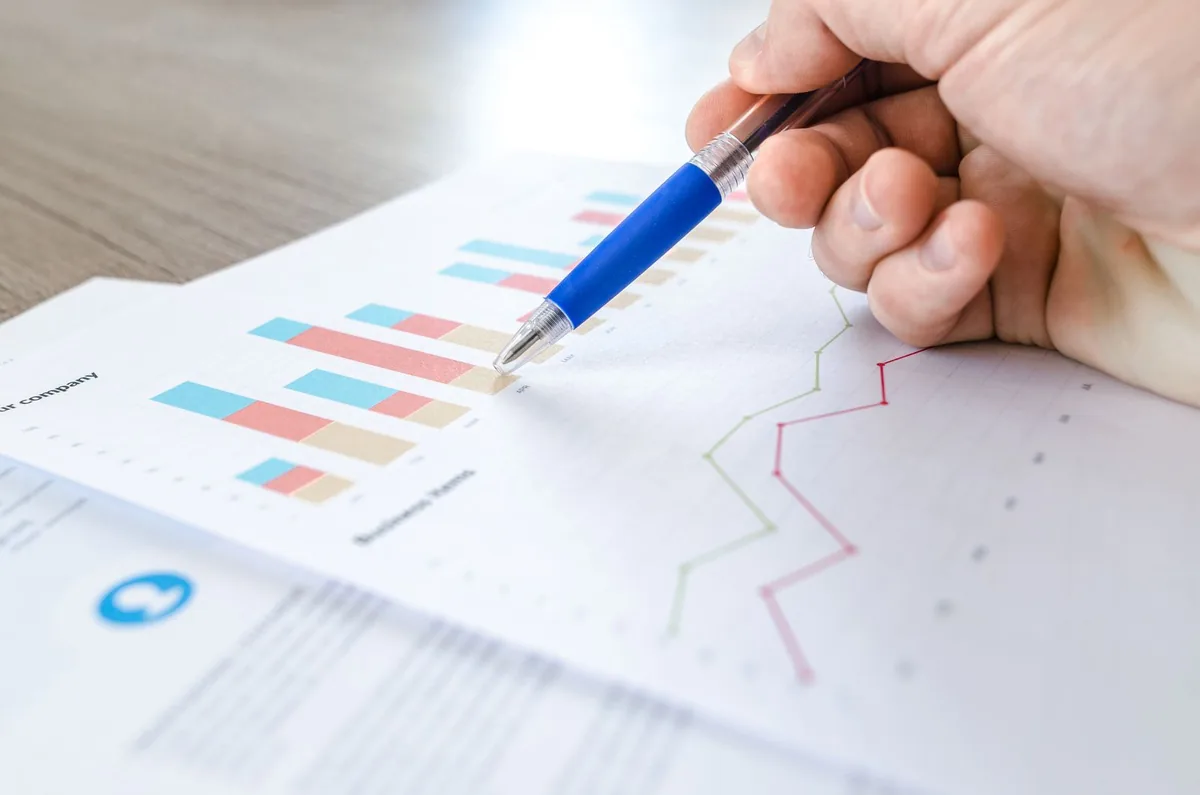 Digital Marketing Agency | ZenWeb Malaysia A person pointing at a performance graph on a printed launch plan
